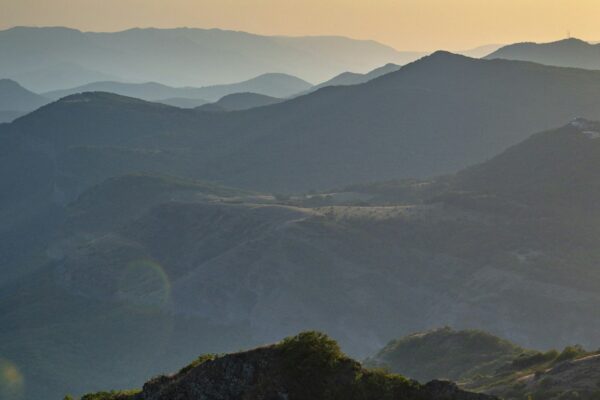 Warm sunset light bathing the Caucasus mountain range in Georgia with misty blue sky